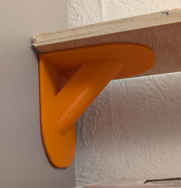 A photo of a custom 3D printed shelf bracket on the wall